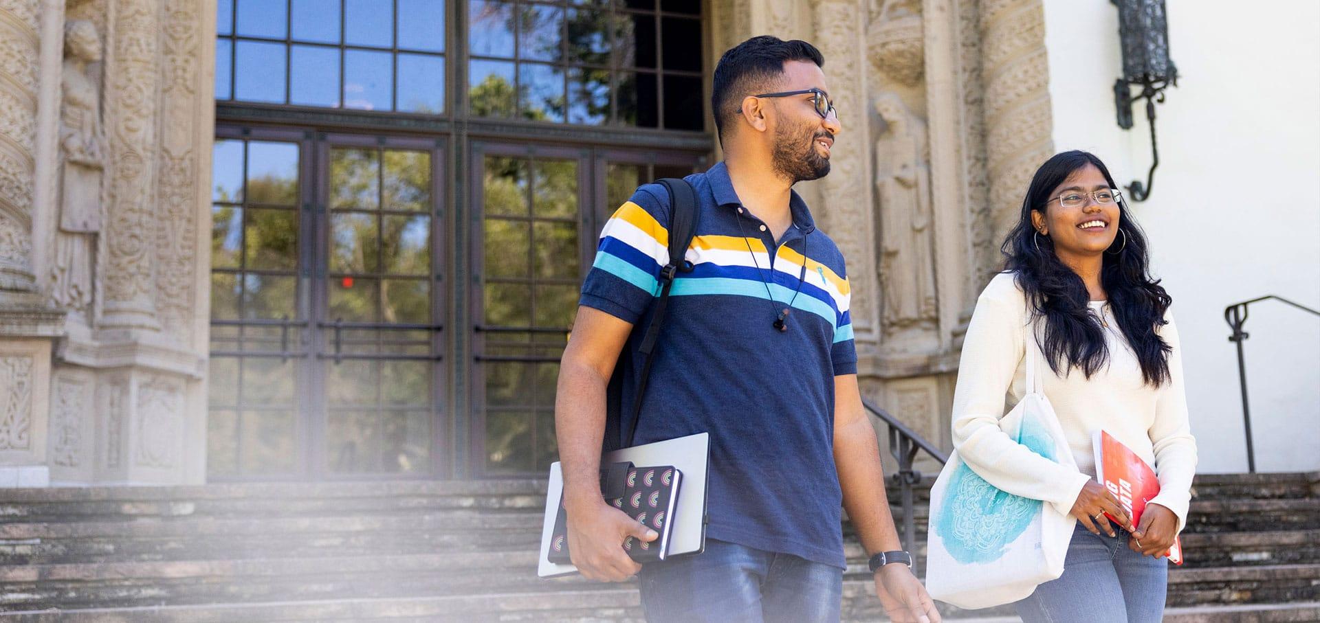 Two students walk down the steps of Littlefield Concert Hall on the Oakland campus.