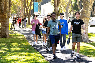 A group of people walking on a sidewalk.