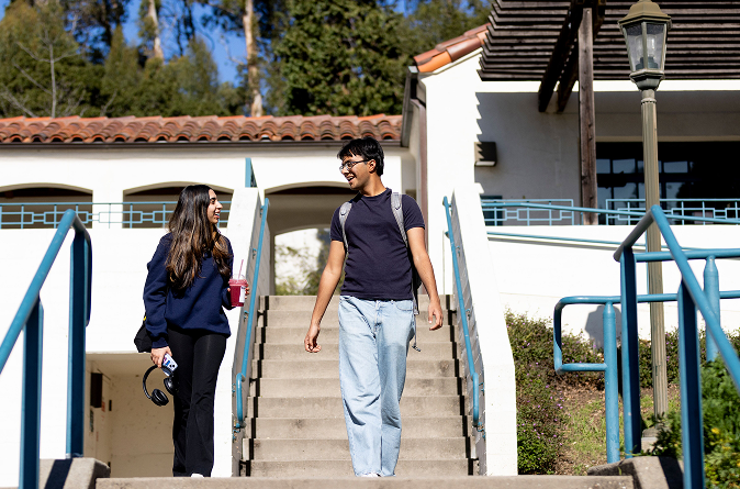 Two students walk down stairs of Vera Long building.