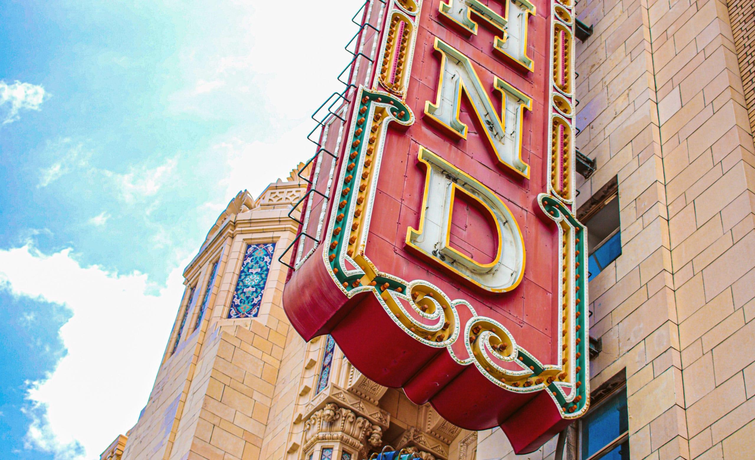 Blue sky with the corner of the Fox Theater building and sign with lights in Oakland, California.